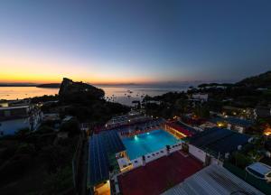 een uitzicht op een zwembad bij zonsondergang bij Hotel Parco Cartaromana in Ischia