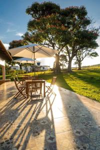 uma mesa e cadeiras sob um guarda-sol num pátio em Hotel Fazenda Tordesilhas em Cocalzinho de Goias