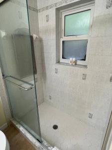 a shower with a glass door and a window at Nice and Comfortable... in Rotunda-West