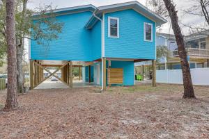 uma casa azul com um alpendre e uma árvore em Oak Island Coastal Home with Covered Deck! em Oak Island