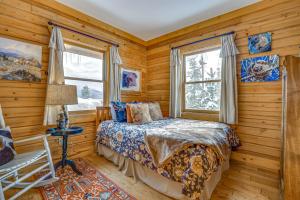 Un dormitorio con paredes de madera y una cama y ventanas. en Private Hot Tub Mtn-View Grand Lake Cabin!, en Grand Lake