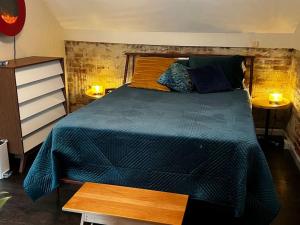 ein Schlafzimmer mit einem Bett mit blauer Decke und 2 Lampen in der Unterkunft NEW! Private Cap Hill Carriage House in Denver