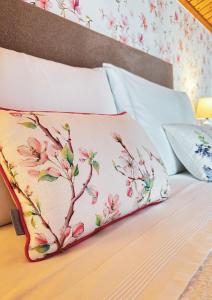 Una almohada en una cama con un patrón de flores. en Teresa Caeiro, en Oia