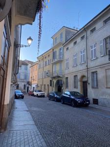 une rue avec des voitures garées sur le côté d'un bâtiment dans l'établissement La Casa nel Vicolo Camera 3, à Casale Monferrato