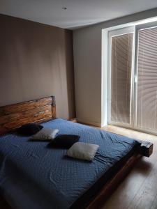 a bedroom with a blue bed with pillows and a window at Bulvár apartmán in Žilina