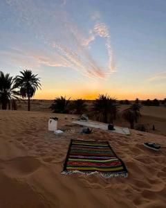 a rug laying on the sand in the desert at Dar Nomad Tagounite in Zagora
