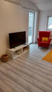 ein Wohnzimmer mit einem Flachbild-TV und einem roten Stuhl in der Unterkunft Dream team in Osijek