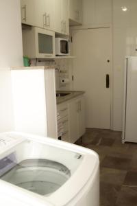 a white kitchen with a sink and a refrigerator at Apartamento Gutierrez 2 in Belo Horizonte