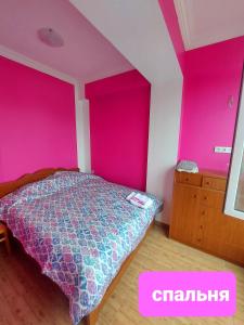 um quarto com paredes cor-de-rosa, uma cama e uma cómoda em Riviera Kobuleti em Kobuleti