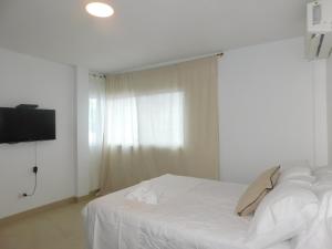 a bedroom with a white bed and a window at Casa Florencia gran piscina in Salinas +54 photos