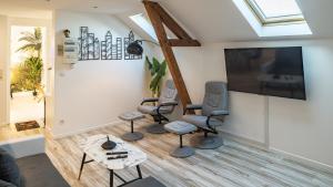 ein Wohnzimmer mit 3 Stühlen und einem Flachbild-TV in der Unterkunft Riverside - Charme et Confort in Troyes