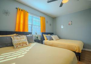 1 Schlafzimmer mit 2 Betten und einem Fenster mit gelben Vorhängen in der Unterkunft Chic Living in Houston: Stylish 2 Bedroom, 2 Bath in Houston