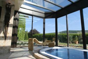 a swimming pool in a house with a large window at Hostellerie Briqueterie & Spa Champagne in Vinay