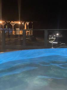 a glass of wine next to a swimming pool at night at Riverside Caravan in Valea Drăganului