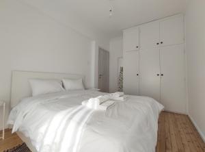 ein weißes Schlafzimmer mit einem großen weißen Bett und weißen Schränken in der Unterkunft CASA Di TRE in Thessaloniki