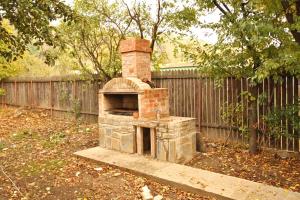 een bakstenen oven in een tuin naast een hek bij VILA IANIS PIATRA NEAMT in Piatra Neamţ