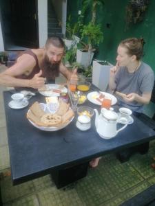 un hombre y una mujer sentados en una mesa con comida en Little Villa Guest House en Ahangama