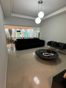 ein Wohnzimmer mit einem Sofa und einem Tisch in der Unterkunft Apartamento com 3 suítes a 300 metros da praia em edifício com piscina in Itapema