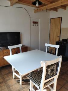 una mesa blanca y sillas en una habitación con TV en Capriche Departamento Temporario, en Río Gallegos