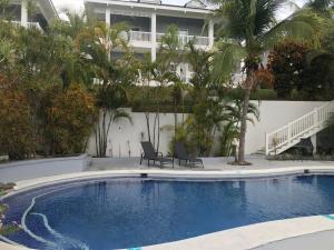 una piscina frente a un edificio con palmeras en The Sanctuary Condominium Playa Azul 6, en Playa Azul