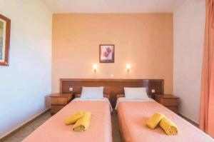 a bedroom with two beds with yellow towels on them at Aleka apartment 2 in Agios Georgios