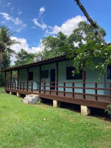 カラグアタトゥーバにあるKerala Guest House Veganの芝生の中に木のポーチがある緑の家