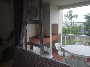 balcón con mesa, sillas blancas y ventana en Laguna la crete 169 uvongo, en Margate