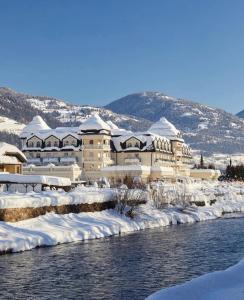 a building covered in snow next to a river at Grandhotel Lienz Business-Wellness & Gourmet in Lienz