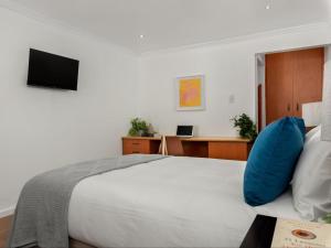 a bedroom with a white bed with a blue pillow at Neighbourgood Ravenscraig in Cape Town