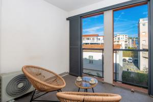 einen Balkon mit 2 Stühlen, einem Tisch und einem großen Fenster in der Unterkunft Studio Port Golfe-Juan Parking Wifi Climatisation Terrasse in Vallauris