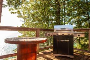 a grill and a table on a deck at The Overlook, Luxury Lakeside Home with Dock in Harrison Hot Springs