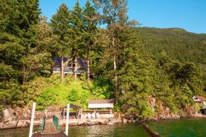 a house sitting on the side of a river at The Overlook, Luxury Lakeside Home with Dock in Harrison Hot Springs