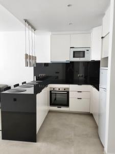 cocina con armarios blancos y encimera negra en Apartamentos San Antonio, en Torremolinos