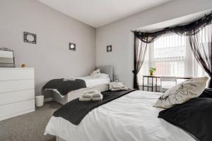 a white bedroom with two beds and a window at City Links-3Bdrm terraced House-Parking-Antonio st in Liverpool