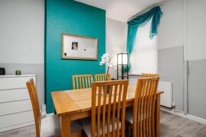 a dining room with a wooden table and chairs at City Links-3Bdrm terraced House-Parking-Antonio st in Liverpool