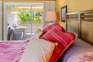 een slaapkamer met een bed met kussens en een balkon bij Studio with mini kitchen, pool and BBQ, Pre-Renovation Summer Sale in Kihei +27 foto's