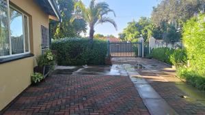 a brick walkway in front of a house with a gate at Green leaves in Mahikeng