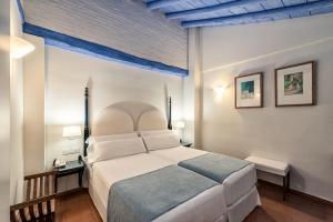 a bedroom with a large white bed with a blue ceiling at Hotel Casa Morisca in Granada