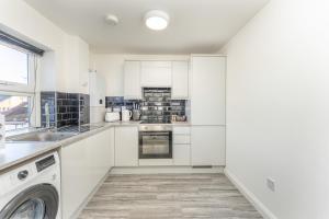 a kitchen with white cabinets and a washer and dryer at 2 bed Luton town centre flat in Luton