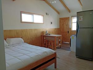 1 dormitorio con 1 cama, nevera y mesa en Ruta 7 en Coihaique
