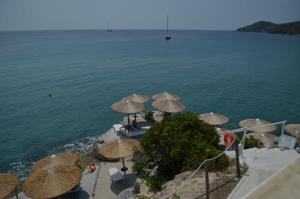 a group of umbrellas on a beach next to the water at Panorama Hotel in Agia Marina Aegina