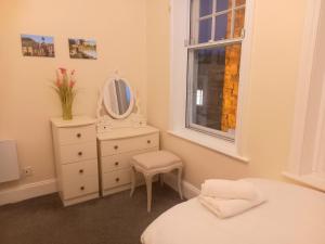 a bedroom with a white dresser and a mirror at Clock Tower Flats Morpeth in Morpeth