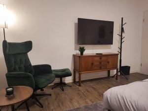 1 dormitorio con TV, silla y mesa en Elegantes 3-Schlafzimmer-Nest, en Hagen