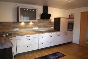 uma cozinha com armários brancos e uma televisão na parede em Ferienwohnung Linde 