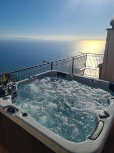 a hot tub on a balcony with the ocean in the background at Villa il Dolce Tramonto in Furore