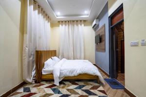 1 dormitorio con 1 cama con sábanas blancas y ventana en The Legends Lodge & Apartments, en Morogoro