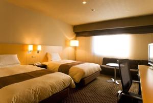 Hotel Metropolitan Morioka في موريوكا: غرفة فندقية بسريرين وكرسي