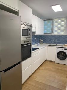 a kitchen with white cabinets and a washer and dryer at Las olas 214 in Maspalomas