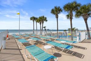 a row of lounge chairs and palm trees on a beach at Boardwalk Beach Resort by Panhandle Getaways in Panama City Beach