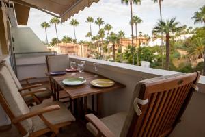 einen Tisch und Stühle auf einem Balkon mit Palmen in der Unterkunft Fantastico Duplex Familiar Dunas Artola in Marbella
